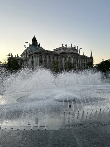 A large fountain in front of an old stone building in Munich, Germany. 