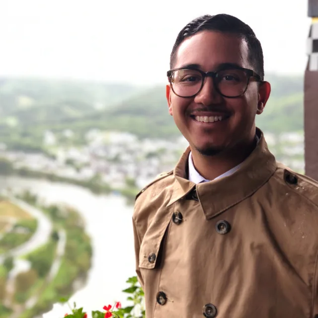 Travel Advisor Anthony Rivera in a tan coat in front of a river.