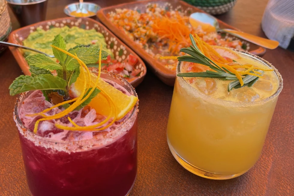 two pink and yellow beverages with mexican cuisine 