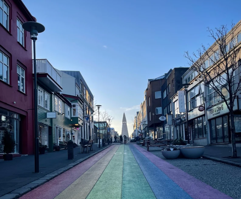 a long street painted rainbow leading towards a monument