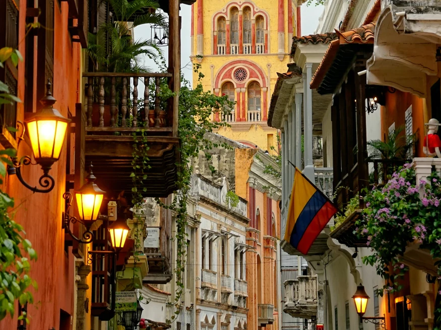 colorful and historic city street with flowers, balconies, and lit lamp posts
