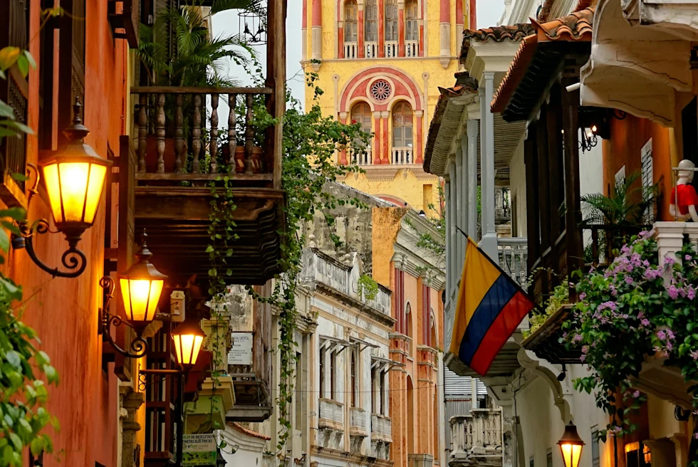colorful and historic city street with flowers, balconies, and lit lamp posts