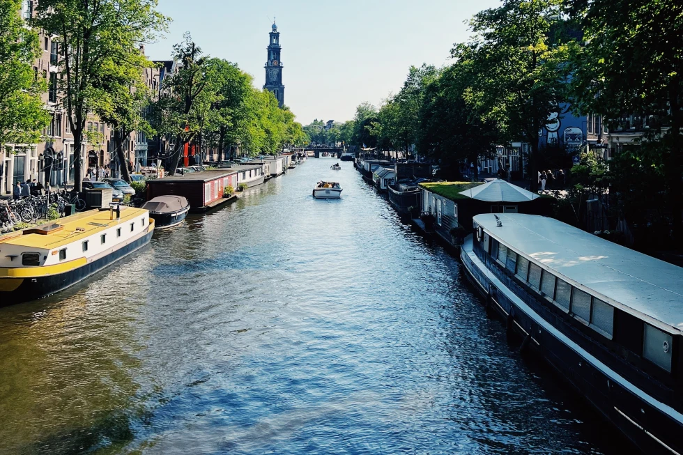 A canal flowing within the city with boats during day time. 