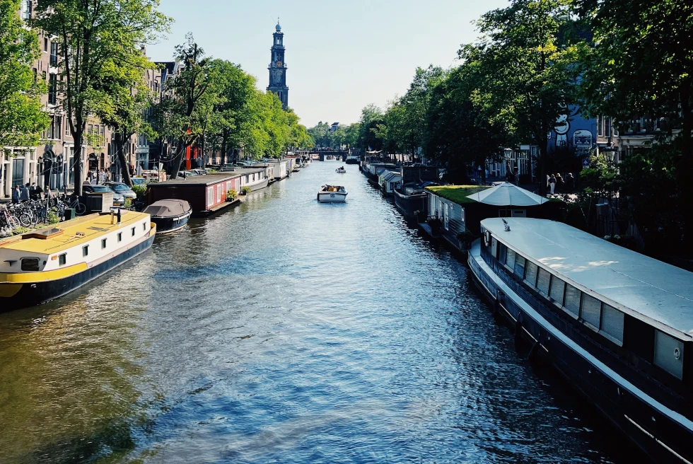 A canal flowing within the city with boats during day time. 