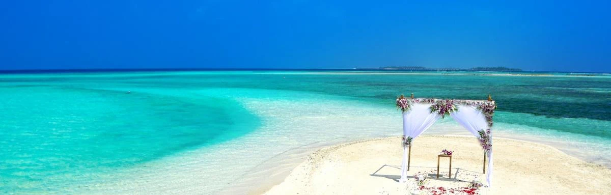 Alter with pink flowers on private white sand beach surrounded by turquoise waters with a bright blue sky