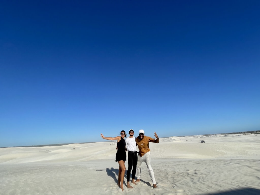 Three people standing on white salt flats against a bright blue sky