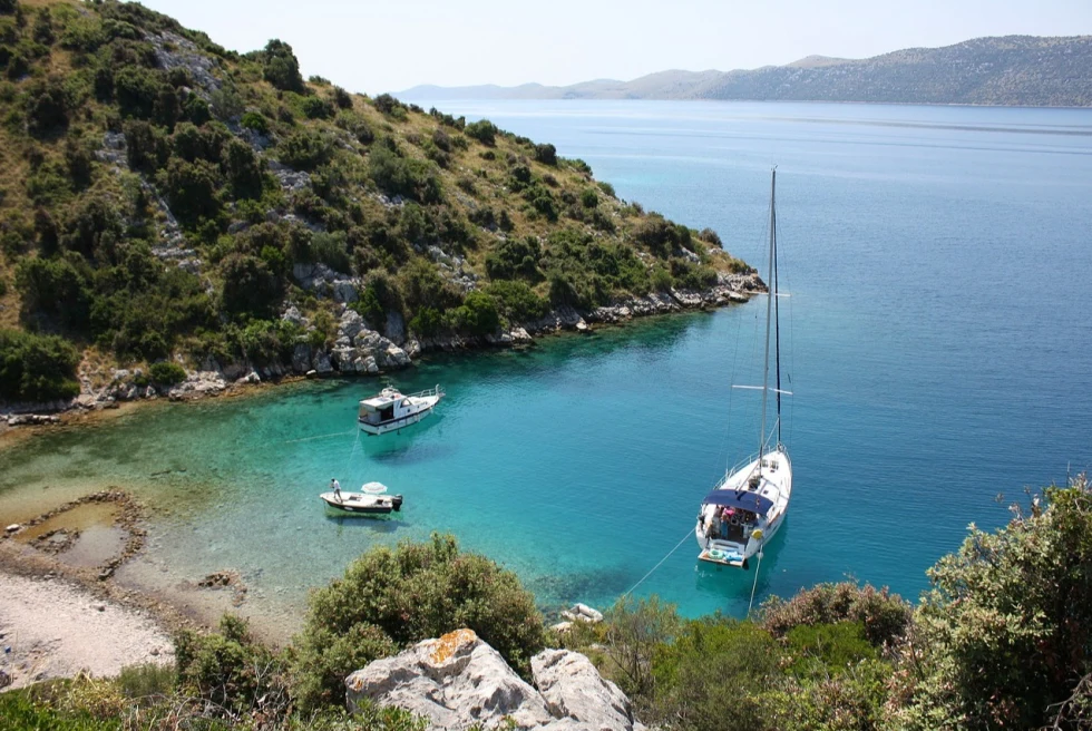 a sailboat and small boats in serene bay on a sunny day