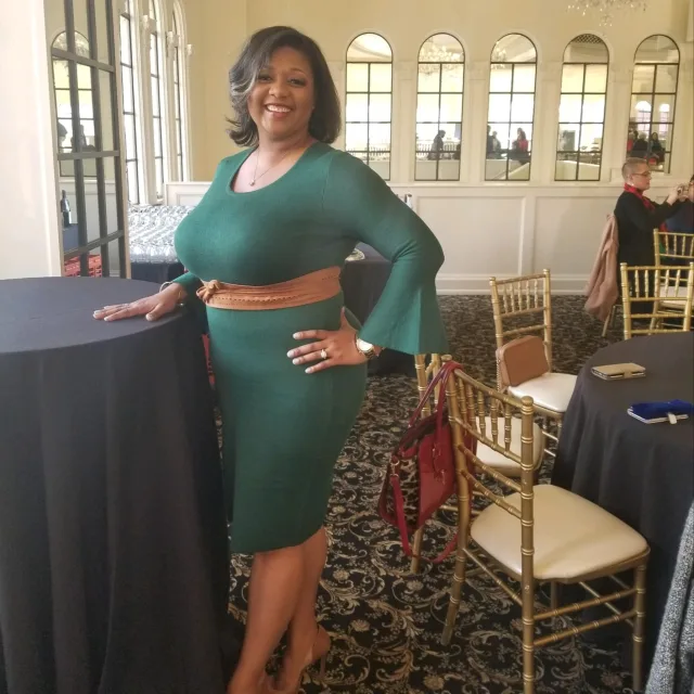 Travel advisor Ebonie Howard posing in a green drees and hand on the hip.