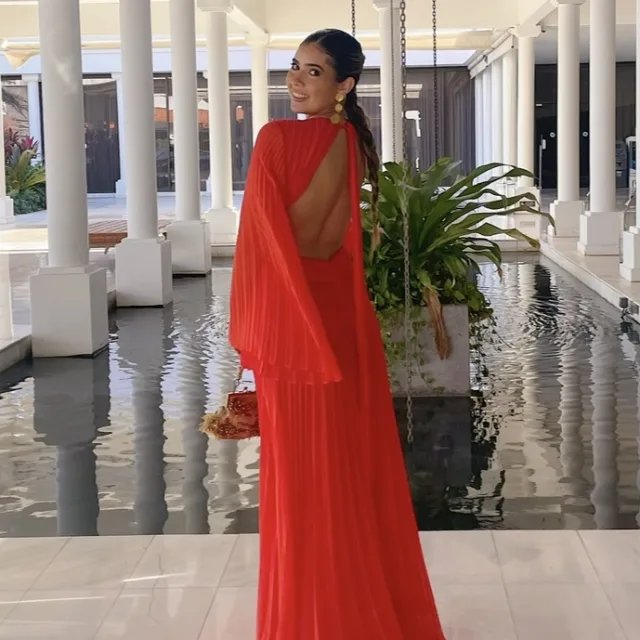 Amanda looking over her shoulder in a red dress in front of a water feature and white pillars.