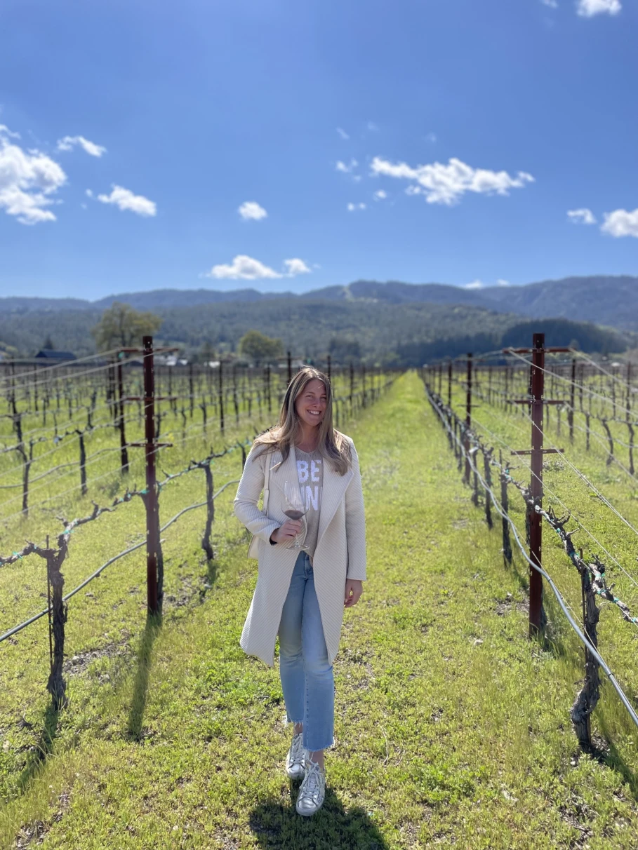A woman posing in a vineyard during day time. 
