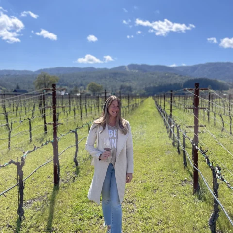 A woman posing in a vineyard during day time. 