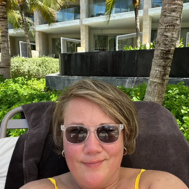 Travel advisor smiling in selfie wearing black sunglasses.