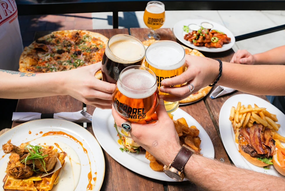 A group of people cheers beer over their Belgian food plates.
