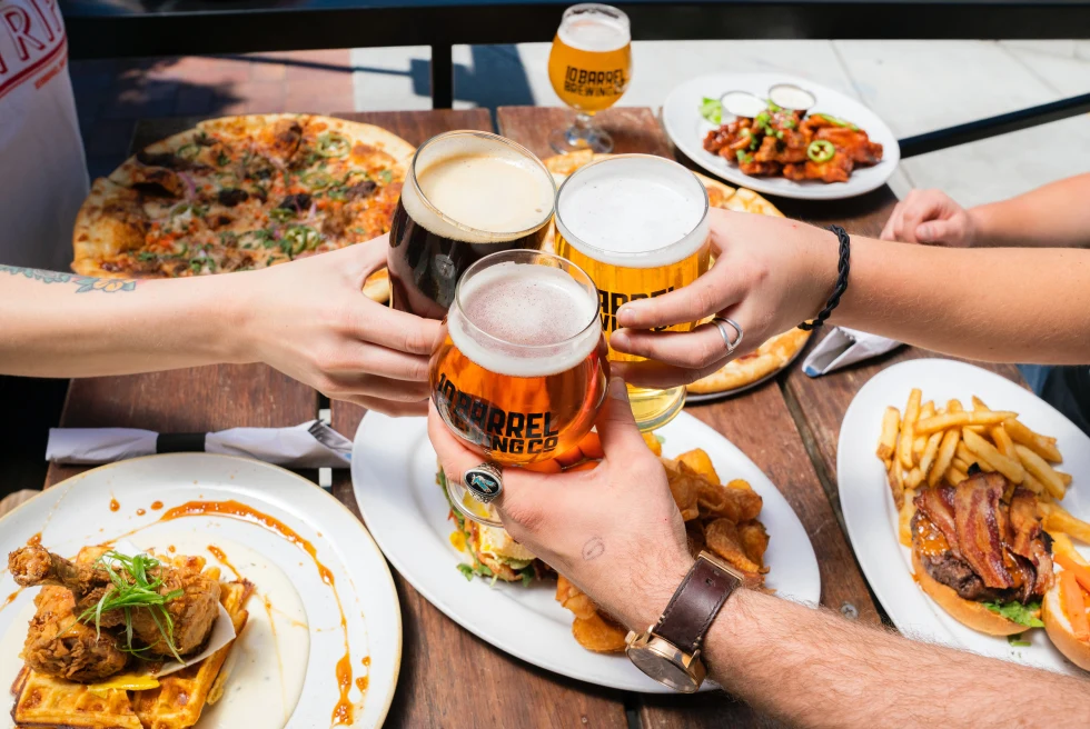 A group of people cheers beer over their Belgian food plates. 