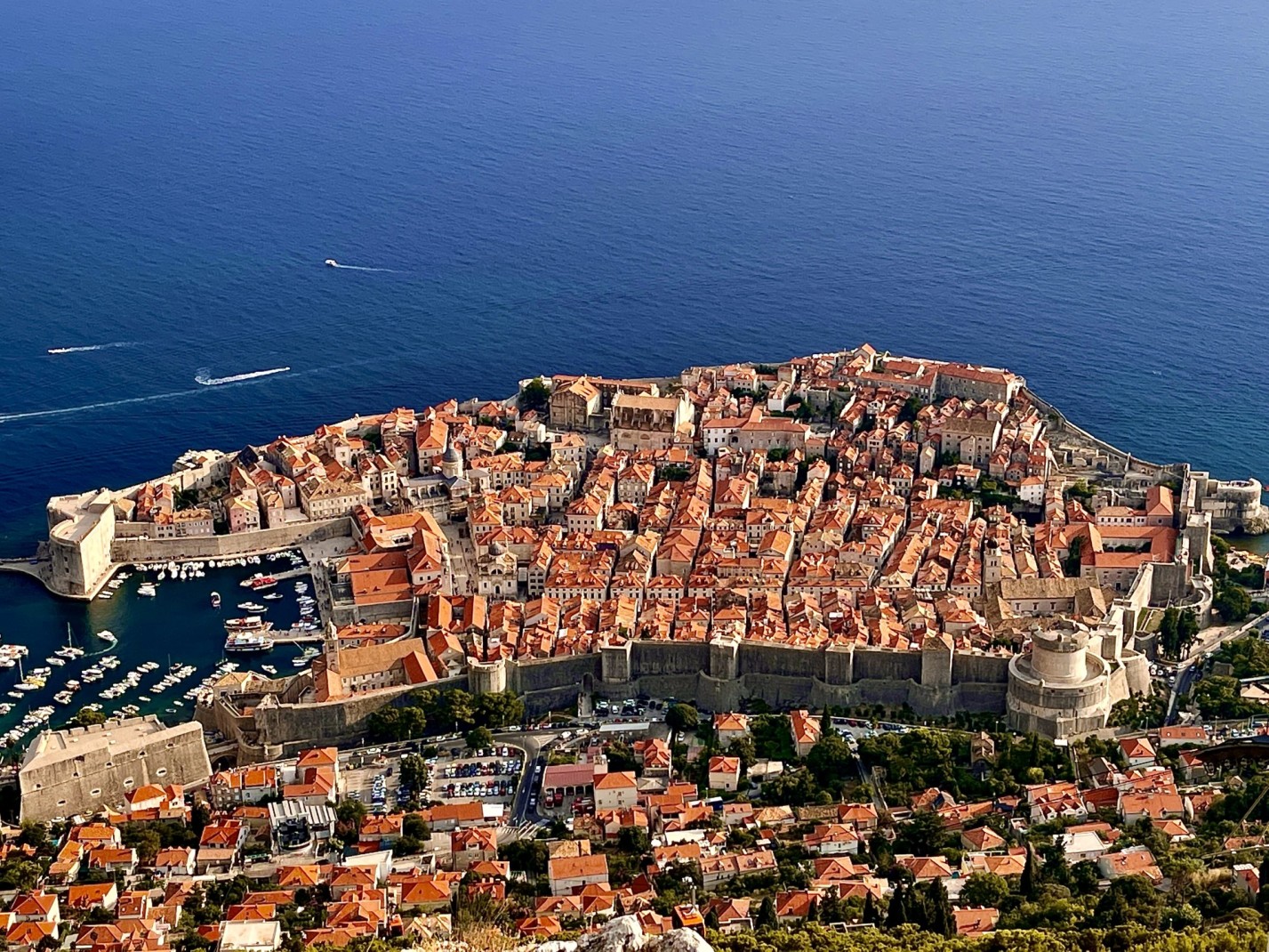 Aerial view of Dubrovnik against deep blue ocean with boats.