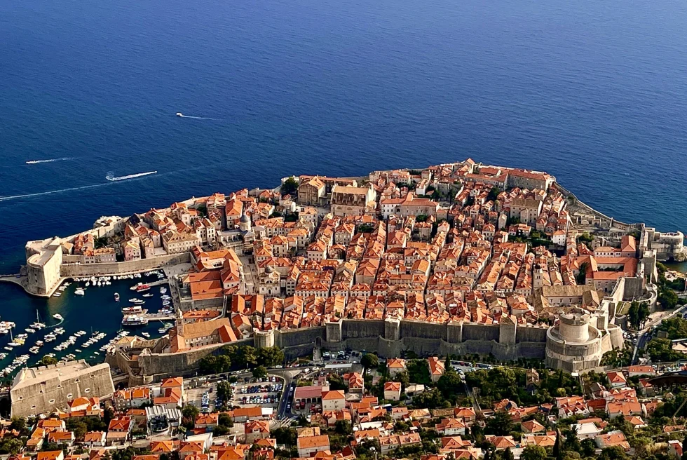 Aerial view of Dubrovnik against deep blue ocean with boats.