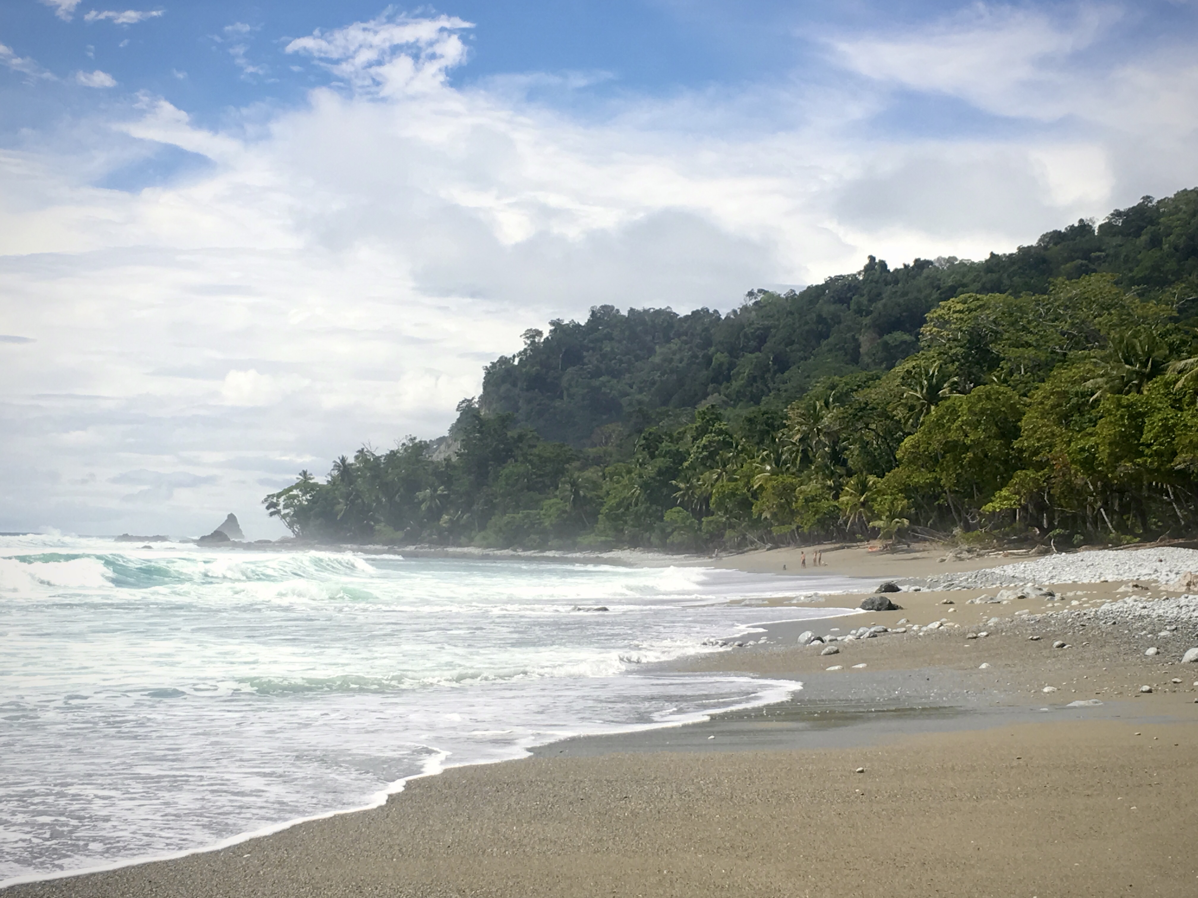 Beach next to ocean and mountains during daytime