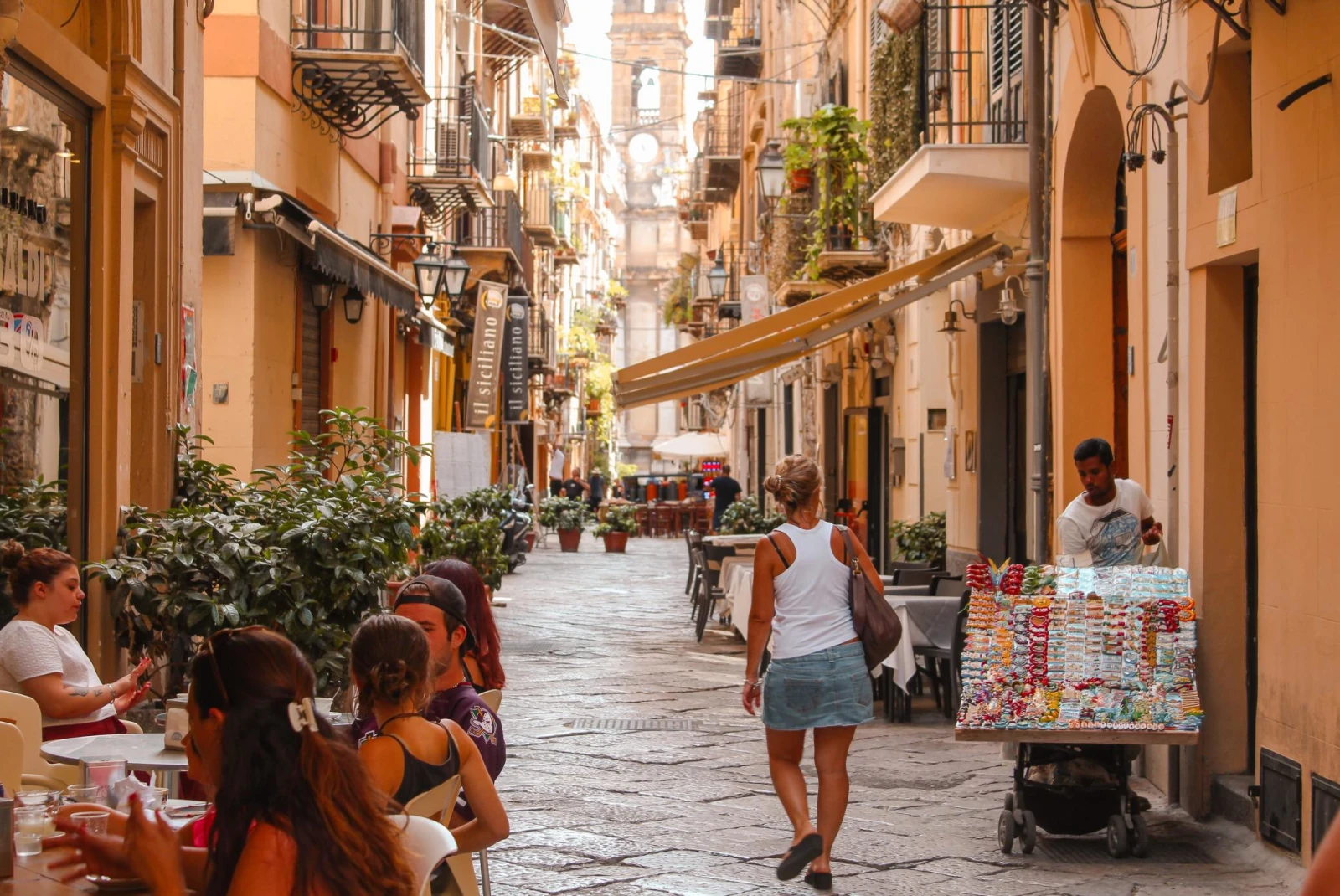 a narrow ancient city street in summer with busy outdoor restaurants 