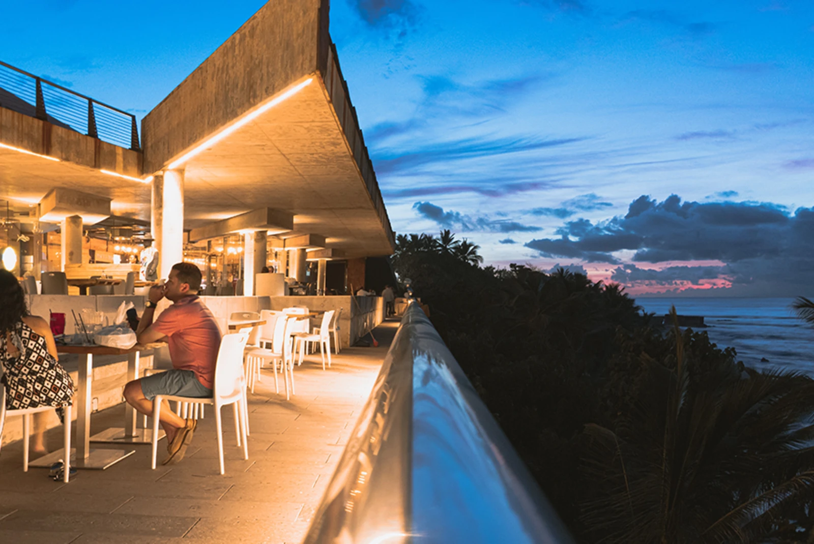 Fine dining in Puerto Rico with blue sky and ocean white lit building and chairs overlooking 