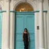 Fora travel agent Caitlyn Johnston stands in front of turquoise door and white archway