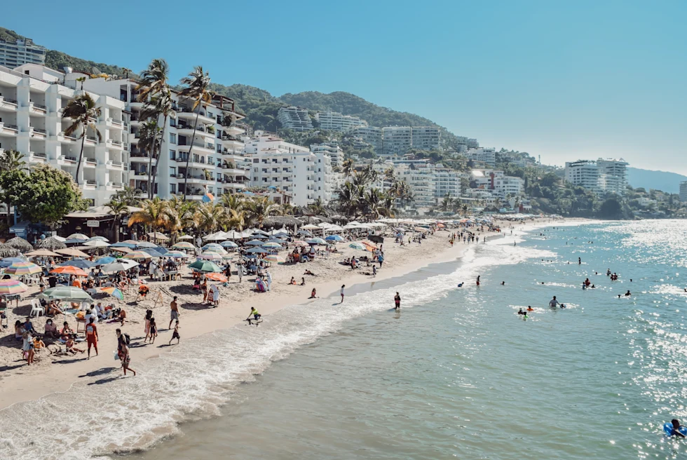 people on the beach next to tall building during daytime