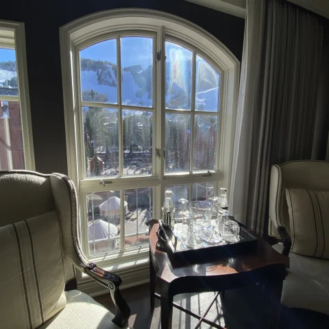 Inside a hotel room of the St. Regis, with a view through the grand windows of Aspen's mountains. 