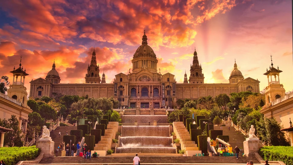 A golden Gothic building in Barcelona, Spain at sunset with pink clouds.
