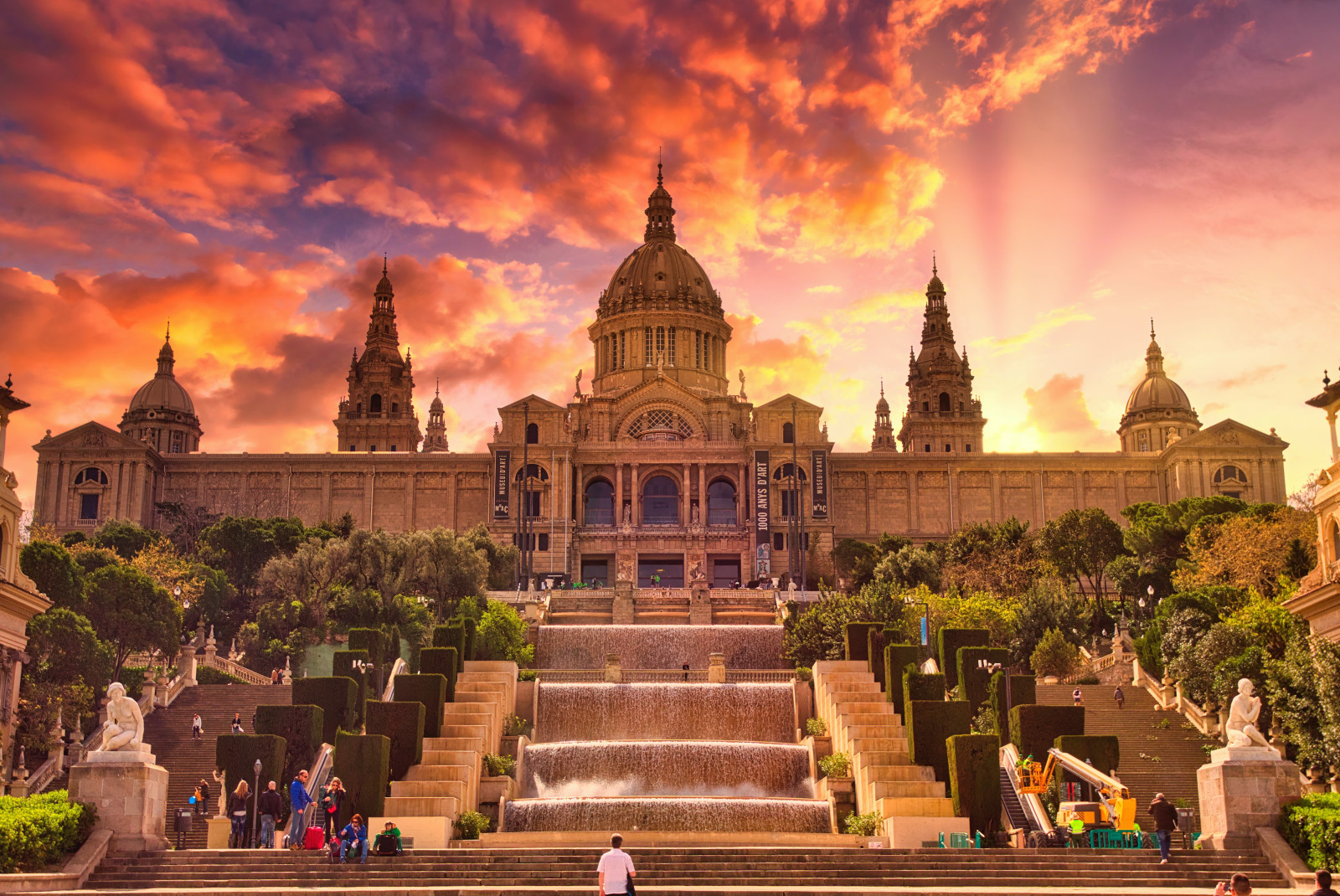 A golden Gothic building in Barcelona, Spain at sunset with pink clouds.