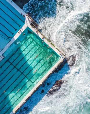 aerial view of people swimming in a pool near the ocean