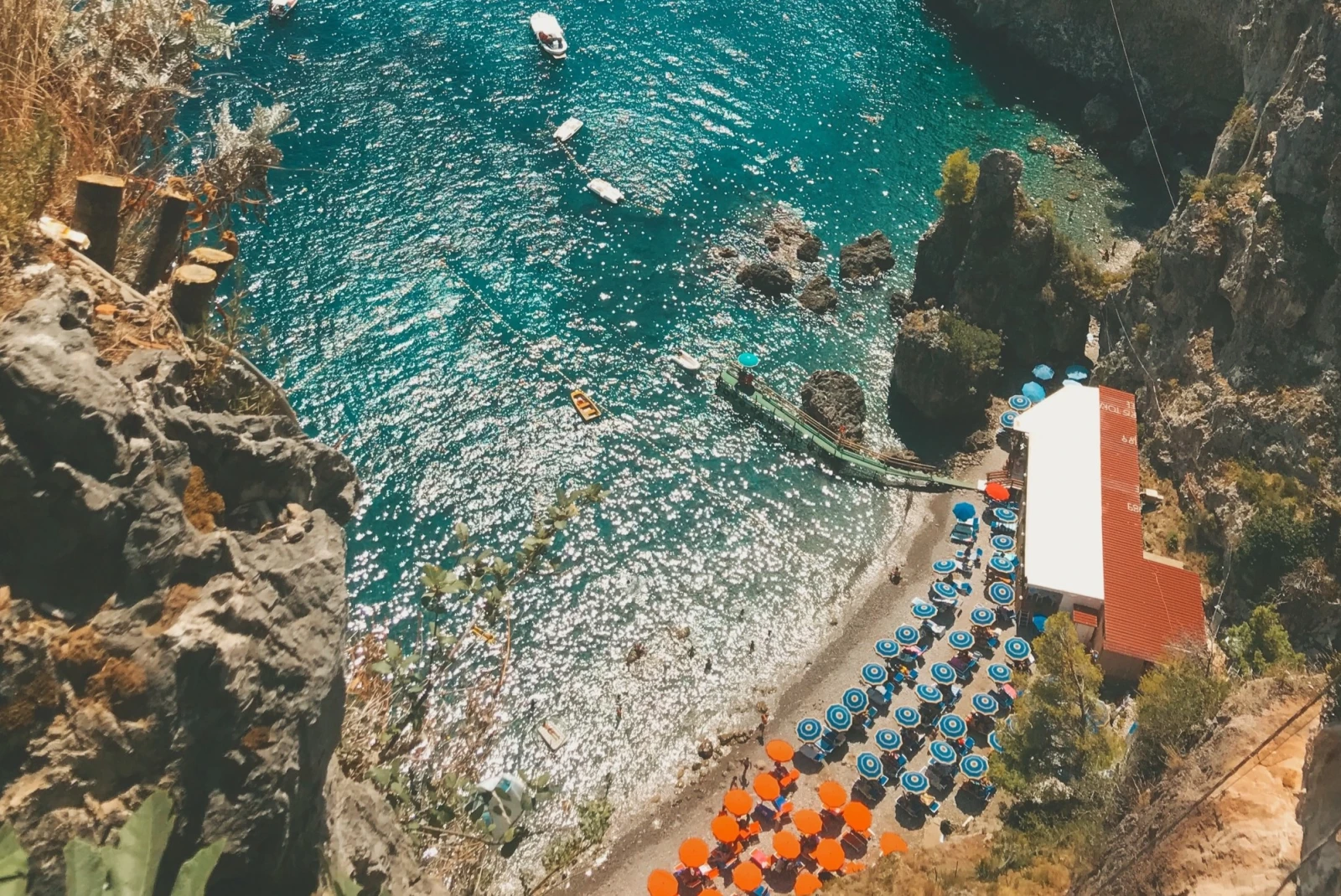 aerial view of a sunny beach with umbrellas in a secluded cove