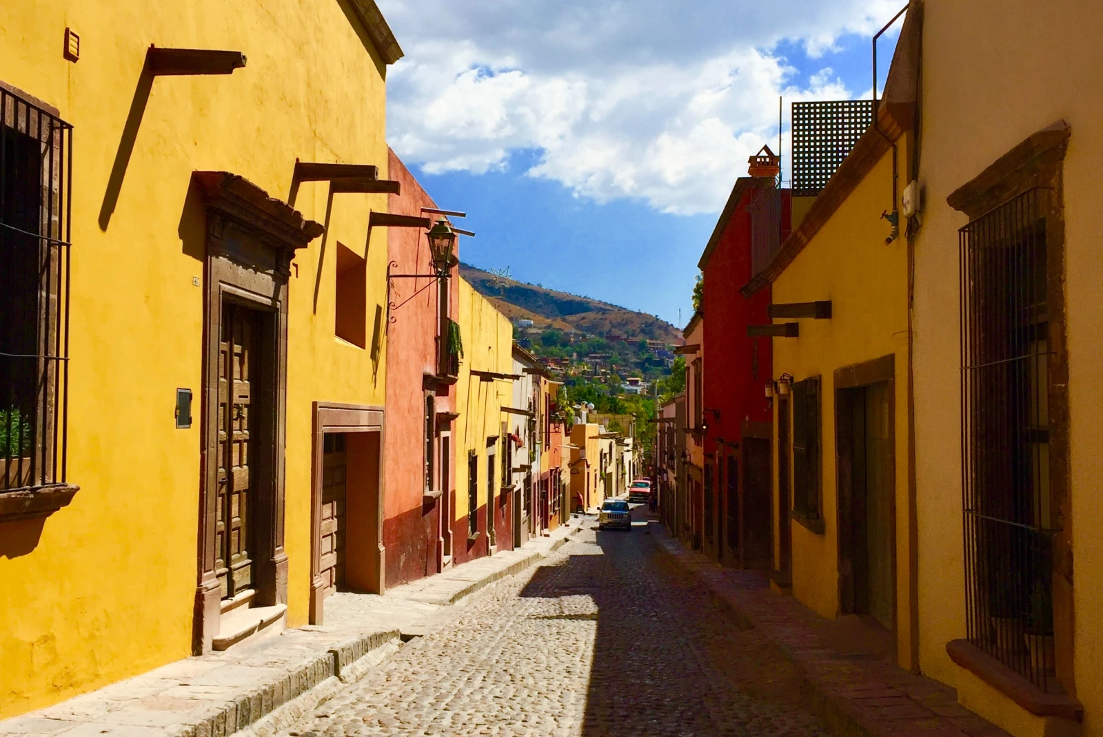 Yellow and pink buildings next to a cobblestone street on a sunny day
