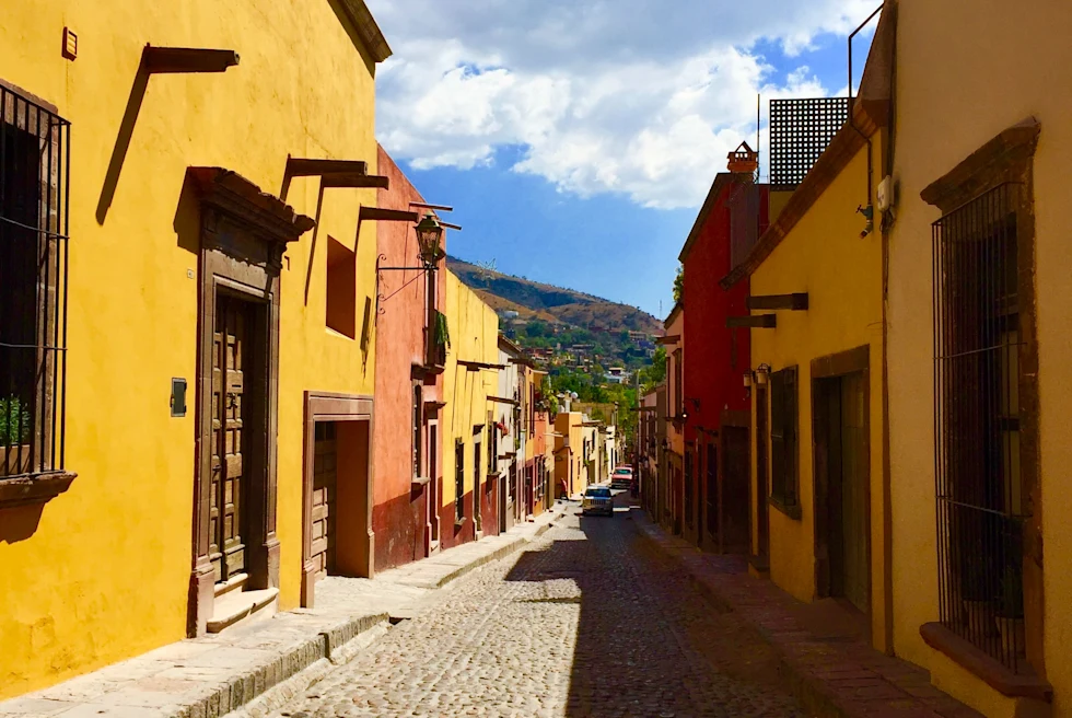Yellow and pink buildings next to a cobblestone street on a sunny day