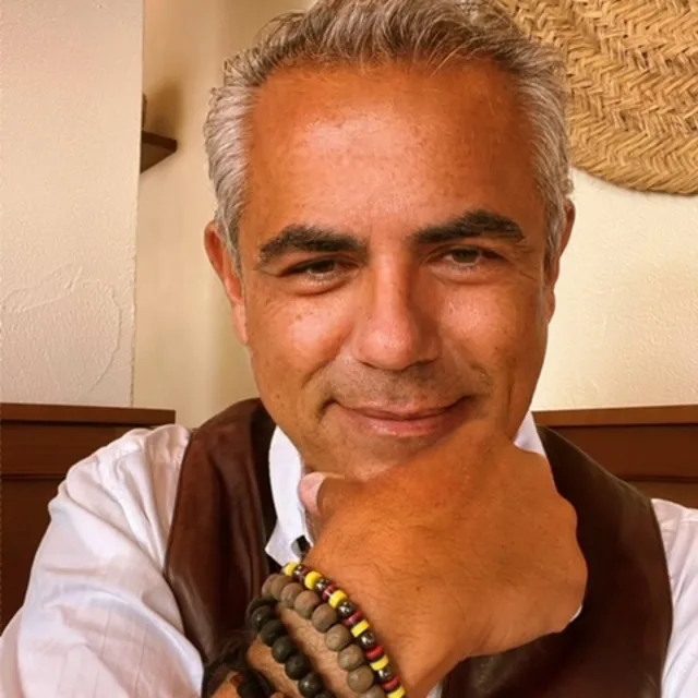 Travel Advisor Joan Carles Gomez Garcia wears a white shirt, brown vest, and brown beaded bracelets