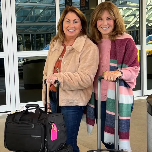 Travel advisors posing with their suitcases at an airport terminal 