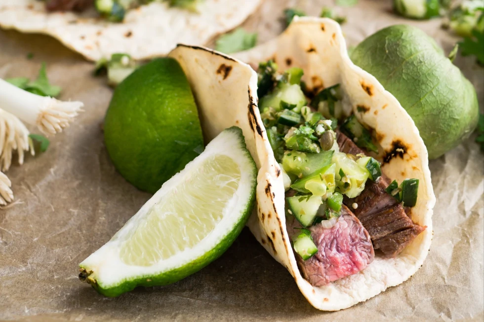steak tacos and limes on parchment paper