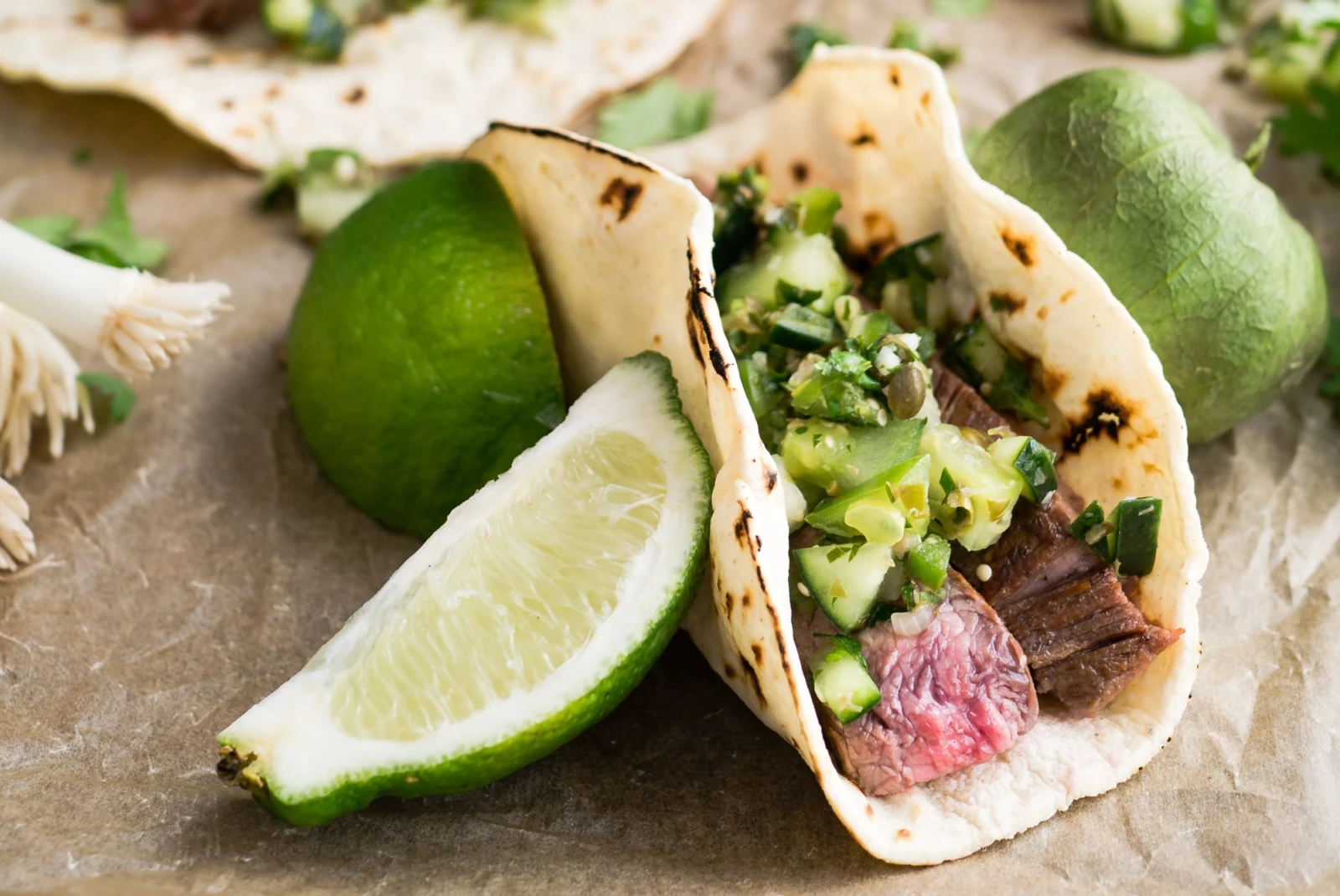 steak tacos and limes on parchment paper