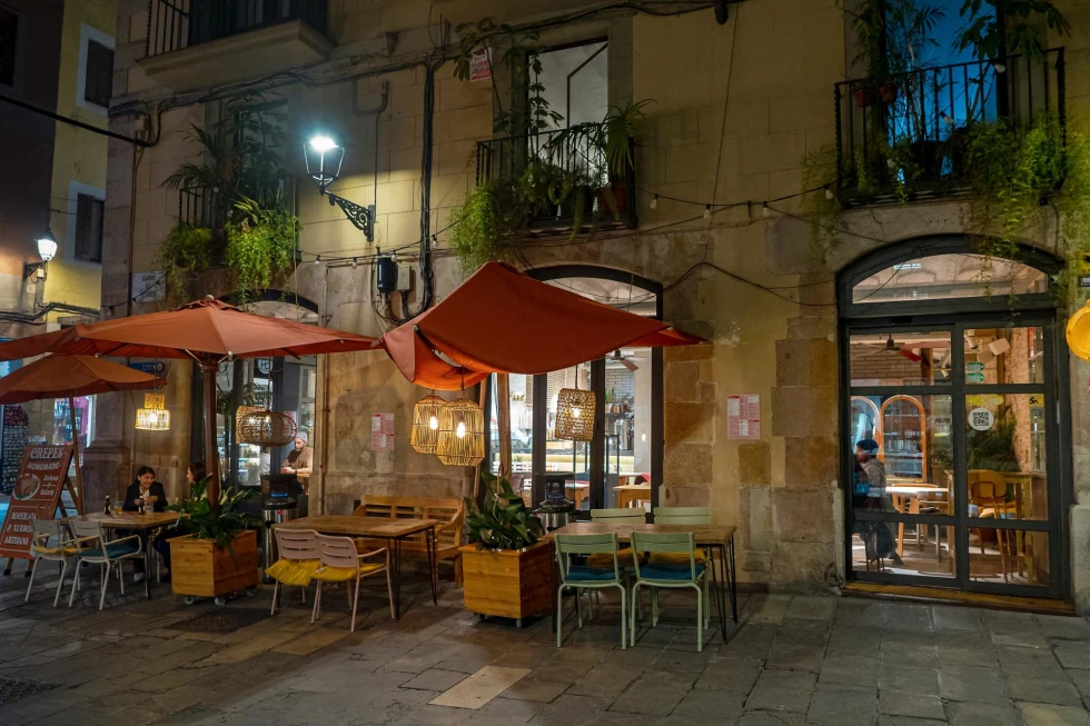outside of a restaurant at night with umbrellas over table and chairs on an old city street