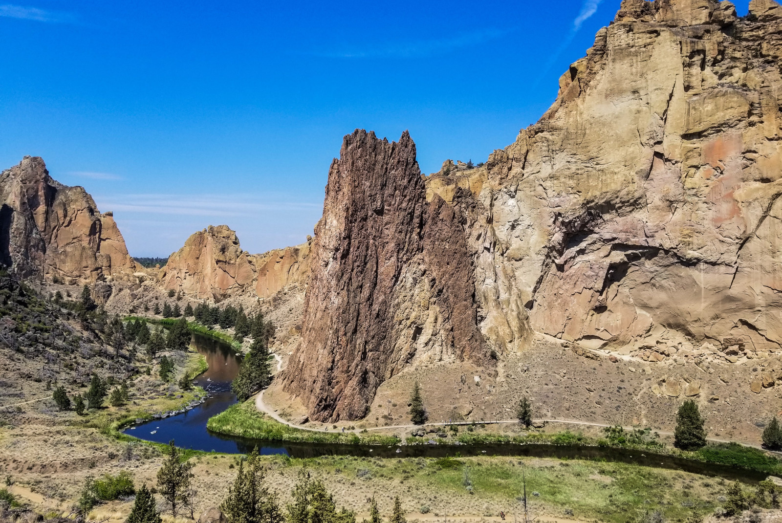 Rocky cliff with grass and winding river on sunny day