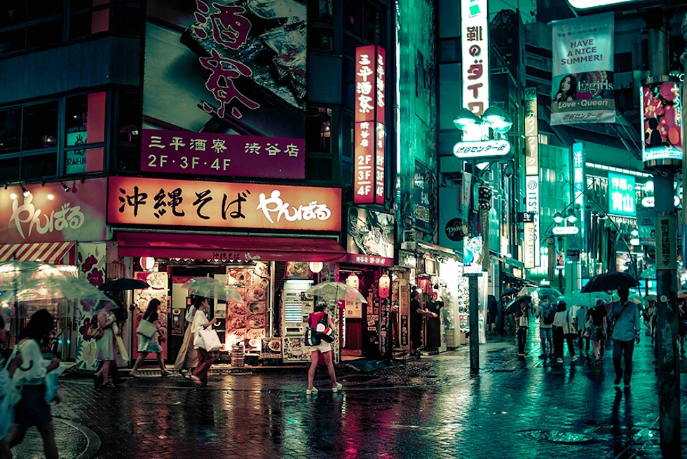 Nighttime in Japan city street raining umbrellas people walking