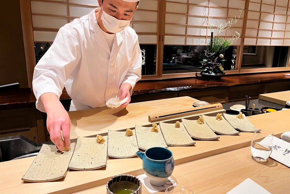 man wearing white chefs coat placing food on tan plates
