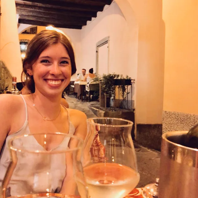 Travel Advisor Emily Ellison in a yellow restaurant with wine.