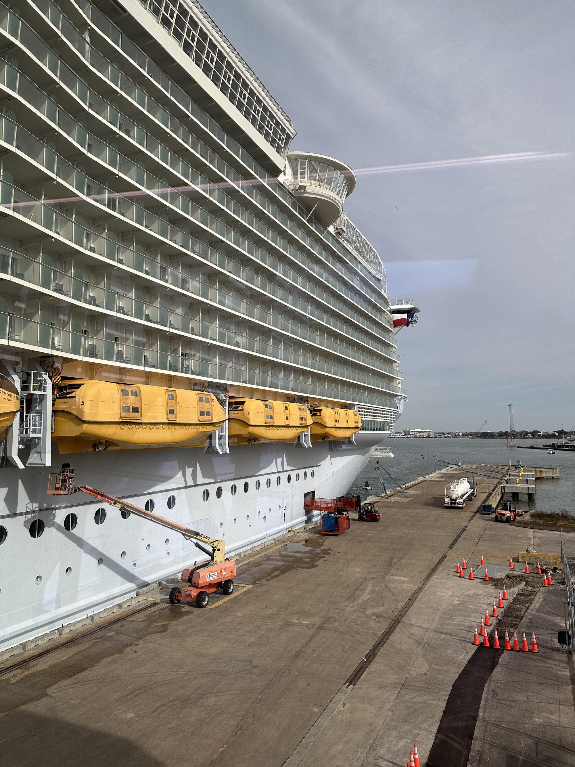 The outside of a cruise ship docked at a harbor with a view of the rooms and balconies
