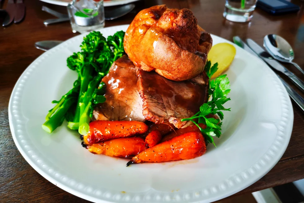 British Sunday roast featuring meant, carrots, greens, brioche and more. 