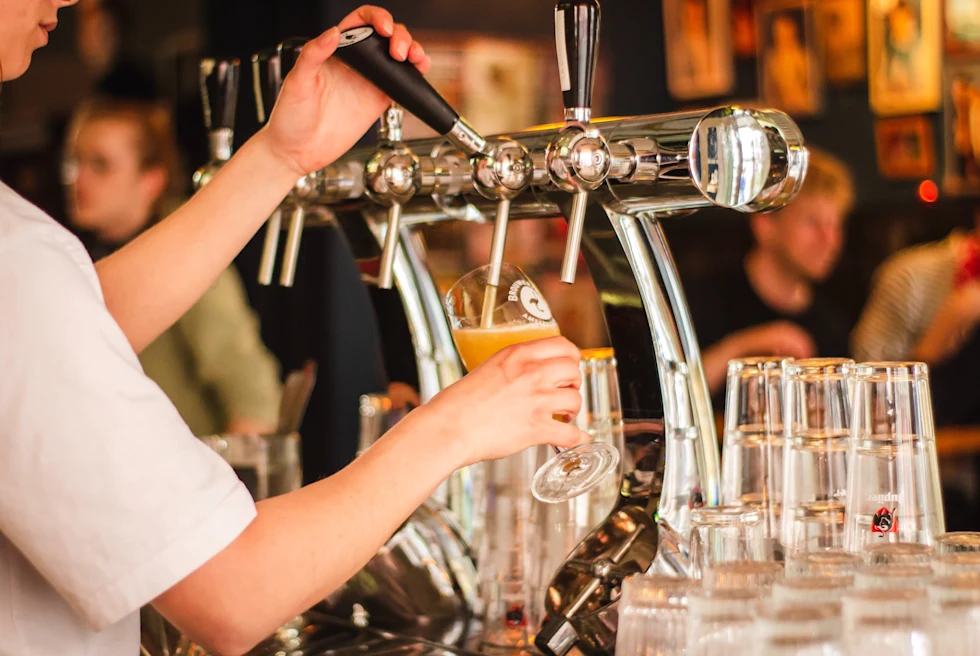 Person pouring draft beer into glass at tavern