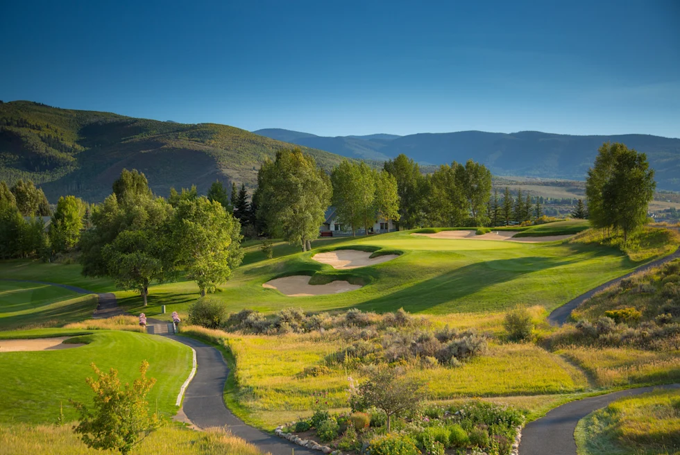 green golf course with mountains in the background during daytime