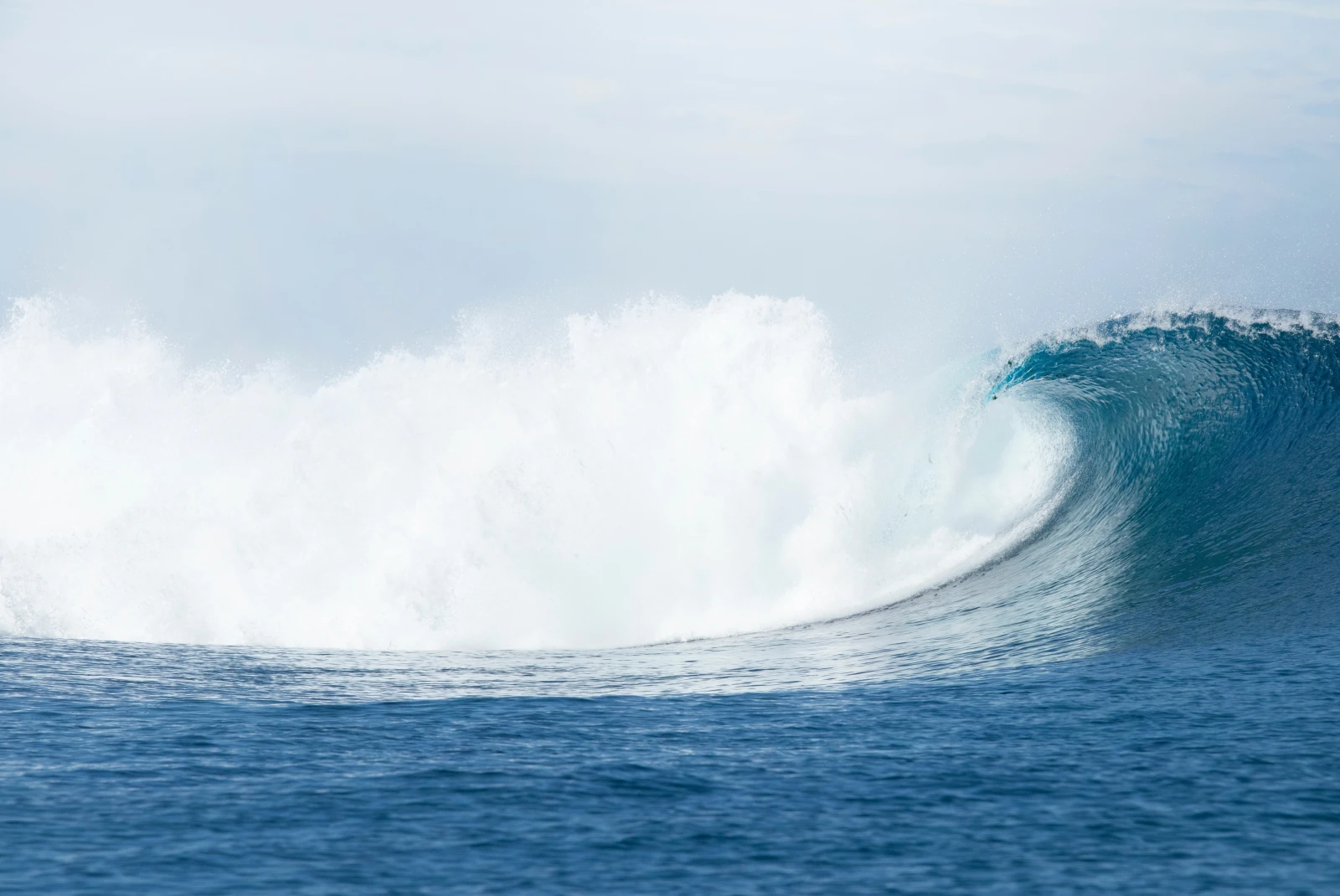 A blue ocean water wave with a white break for surfing in Fiji.