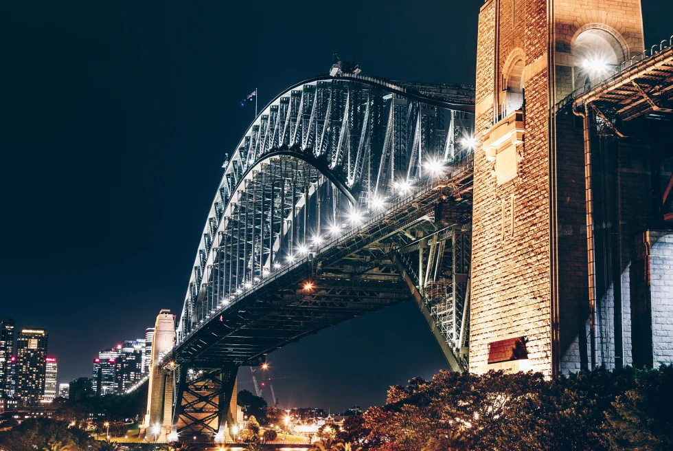A bridge with buildings behind during night time. 
