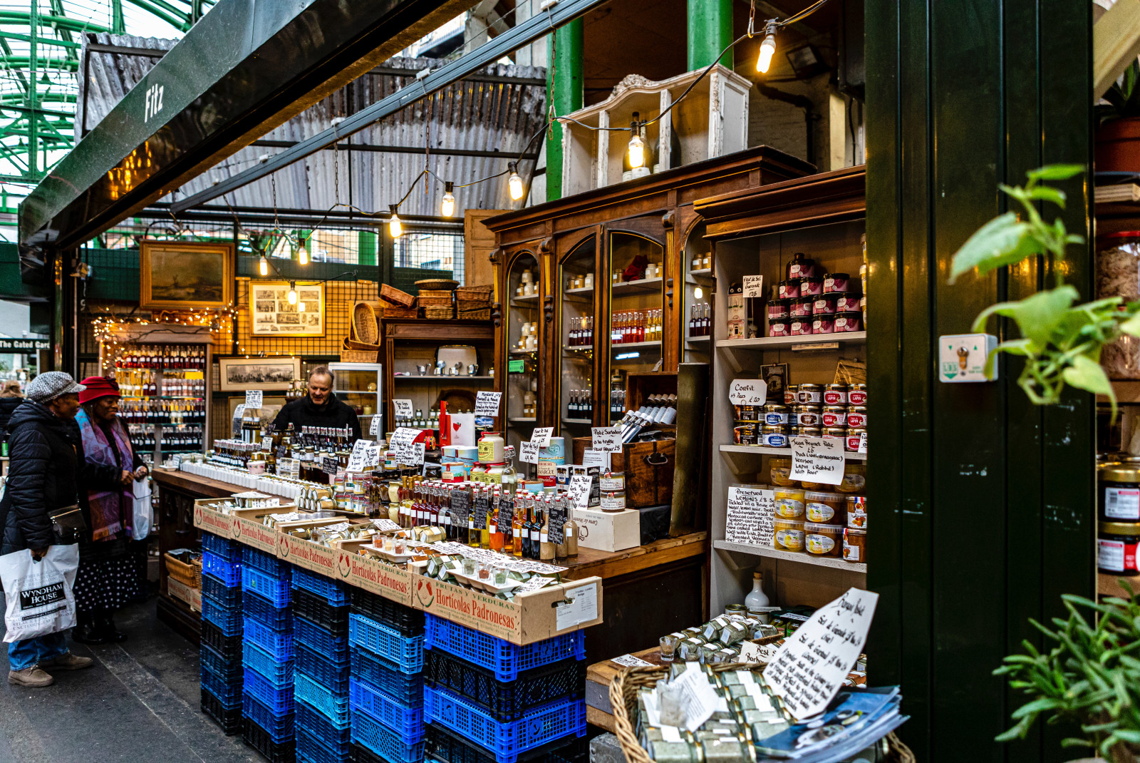 Two women speaking to a male cashier at the London Borough Market.