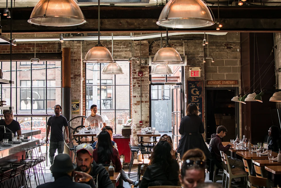 People sitting at tables in room with large windows during daytime