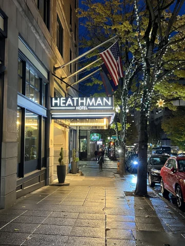 The Heathman Hotel exterior with an American flag on top of it and trees next to it.